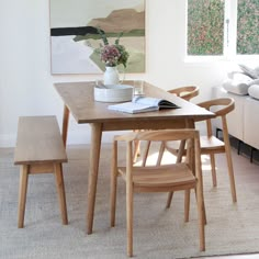 a wooden table with two chairs and a vase on it next to a couch in a living room