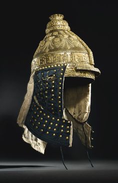 an old helmet with gold rivets on the side and a black back ground