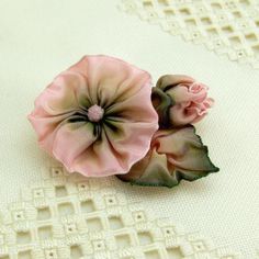 two pink flowers sitting on top of a white table cloth