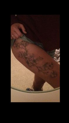 a woman's leg with flowers on it in front of a mirror