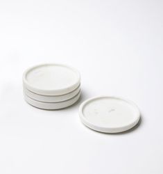 three white plates sitting next to each other on top of a white tablecloth covered floor