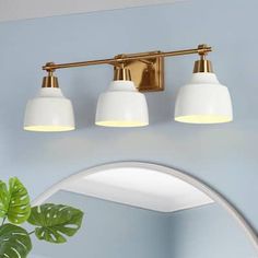 three light bathroom fixture with white glass shades and gold trim on the wall above it