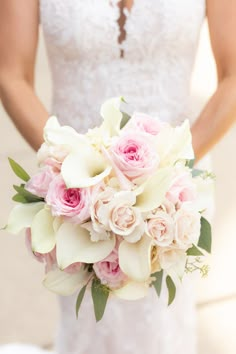 a bride holding a bouquet of pink and white flowers