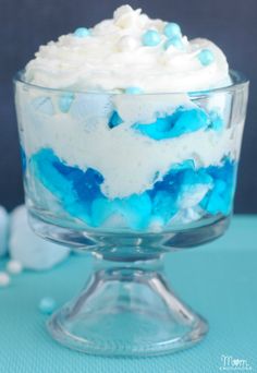 there is a blue dessert with white frosting in the bowl and on the table