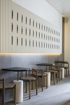 several tables and stools are lined up against the wall in front of a white panel