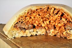 an open pita bread filled with pasta and meat on top of a wooden cutting board