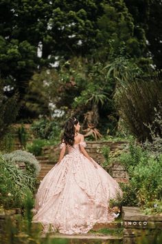 a woman in a pink dress is standing on some steps and looking into the distance