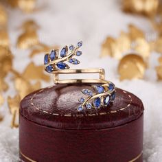 a gold ring with blue stones sits on top of a wooden box surrounded by golden stars