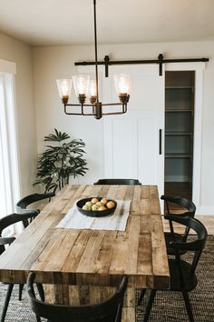 a dining room table with fruit on it and lights hanging from the ceiling over it