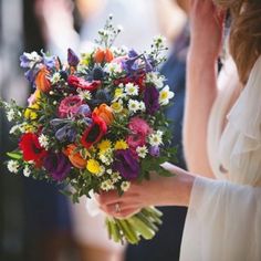 a woman holding a bouquet of colorful flowers