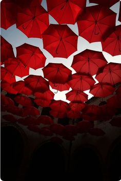 many red umbrellas are hanging from the ceiling