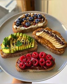 there are four different types of breads on the plate with berries, bananas and kiwi