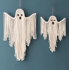 two white halloween decorations hanging from hooks on a wall, one with eyes and the other with fringes