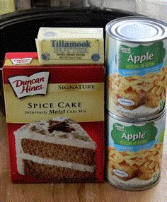 two cans of apple cake next to a can of cinnamon apples and some other desserts