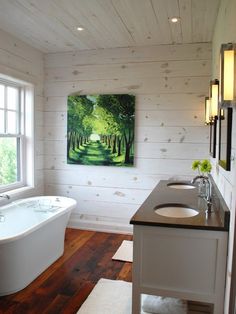 a bathroom with two sinks and a bathtub next to a painting on the wall