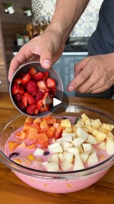 someone is mixing fruit in a bowl on the table