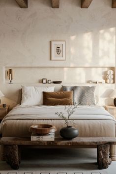 a bed sitting in a bedroom next to a table with a vase on top of it