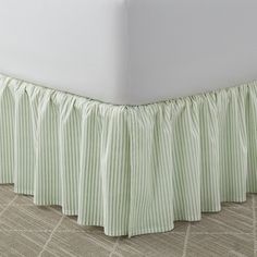 a bed with a green and white striped bedskirt on it's side