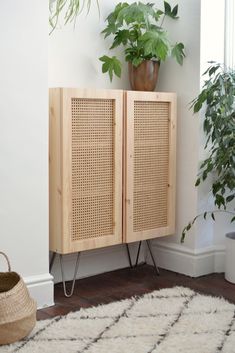 a wooden cabinet sitting next to a potted plant