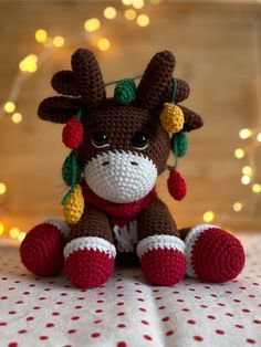 a crocheted stuffed animal sitting on top of a table next to a christmas tree