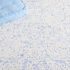 a blue and white rug with a blanket on it's side next to a bed