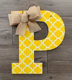 the letter p is painted yellow and has a large bow on it's front