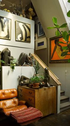 a living room filled with lots of furniture and art on the wall next to a stair case