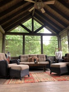 a living room with couches and chairs inside of a wooden roofed area surrounded by trees