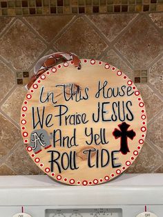 a wooden sign that says in this house we praise jesus and yel roll tide