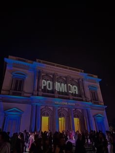 people are standing in front of a building with the word polimia projected on it