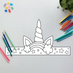 a coloring page with pencils and markers next to the unicorn's head, which is surrounded by stars