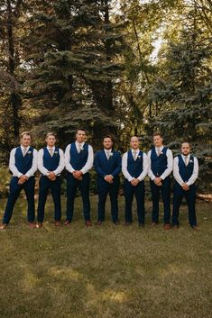 Groomsmen standing with hands crossed in blue suit and tux Navy Blue And Cream Groomsmen Suits, Groom In Suit Groomsmen In Vest, Navy Vest Khaki Pants Groom Attire, Groomsmen Attire April Wedding, Trending Groomsmen Attire, Male Wedding Party Attire, Navy Blue Groomsman Suit, Navy Suit With Vest Wedding, Navy Mens Wedding Attire