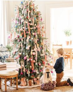 a young boy decorating a christmas tree in the living room with ornaments on it