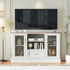 a living room with a white entertainment center and gold trimmings on the doors