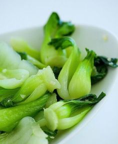 a white bowl filled with green vegetables on top of a table