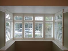 an empty window with white shutters in the corner