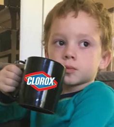 a young boy holding a black mug with the word clorox on it