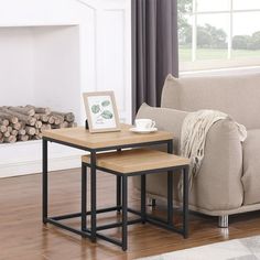 two tables sitting on top of a wooden floor next to a couch in front of a fire place