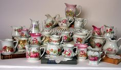 a table topped with lots of different kinds of cups and saucers on top of a book