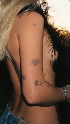 the back of a woman's body with tattoos on her left arm and shoulder