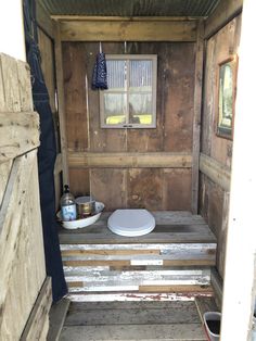 the inside of a small wooden shed with a toilet and sink in it's stall