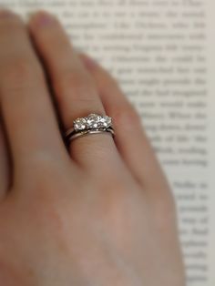 a woman's hand holding an engagement ring with three stones on top of it