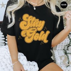 All of our Stay Gold t-shirts are handmade to order on an ultra soft shirt that will quickly become your go to apparel item! You will never want to take it off! Our Outsiders tee's are printed with eco-friendly water based ink that feels good and lasts longer!  ♥The details♥ This unisex t-shirt is crafted from soft, breathable fabric for ultimate comfort. Printed with an eco-friendly water-based ink, this shirt not only looks great but also supports sustainable practices. The unisex sizing allows for a versatile fit, but we suggest sizing up for a more relaxed look. To keep your shirt looking its best, we recommend washing it on cold and either hanging it to dry or tumble drying it on low heat. Be sure to avoid ironing directly on the design to preserve the vibrant print. For a perfect fit Gold Shirts, Gold Shirt, Stay Gold, Movie Shirts, Sustainable Practices, Comfort Colors, Breathable Fabric, Favorite Outfit, Looks Great