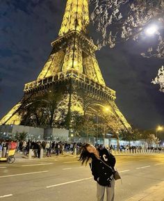 a woman standing in front of the eiffel tower at night