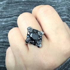 a woman's hand with a black diamond ring on top of her finger,