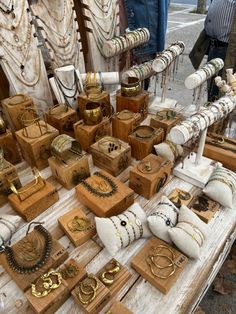 a table topped with lots of wooden boxes covered in gold rings and necklaces on display