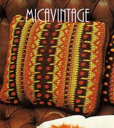 a crocheted pillow sitting on top of a brown couch