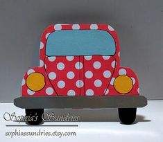 a red and white truck with polka dots on it's side, sitting in front of a gray background