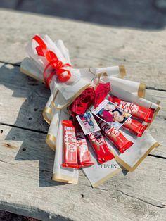 a bunch of candy wrapped in paper on top of a wooden table next to a red bow