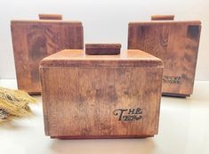 three wooden boxes sitting next to each other on a white counter top with wheat in the background